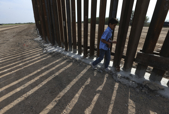 미국 텍사스 리오그란데에 거주하는 디에고 페냐가 18일(현지시간) 텍사스 강철 장벽 옆을 걸어가고 있다. 그레그 애벗 텍사스 주지사는 이날 기자회견에서 불법 이민을 막기 위한 새로운 장벽 건설 계획을 발표했다. <AP=연합뉴스>